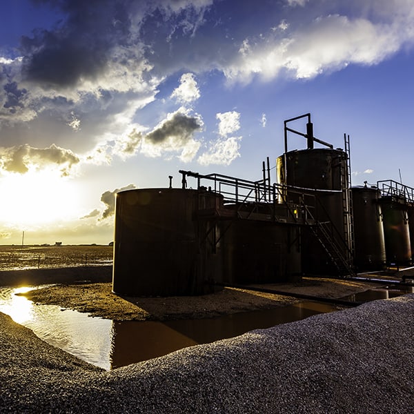 Farm Oil Storage Tanks With Stormy Sunset And Sunflare